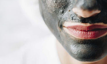 woman with natural charcoal face mask on face