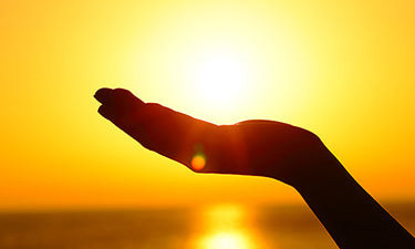 banner for tan accelerator sun cream category featuring hand with sunshine behind