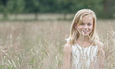 banner for organic children category featuring girl standing in field of long grass