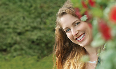 banner for natural and organic toothpaste category with lady smiling in garden